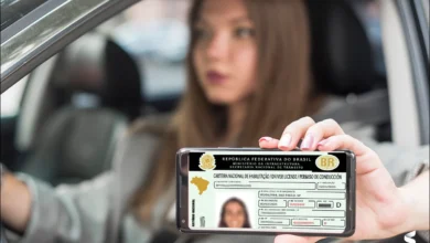 Pessoa mostrando sua CNH digital no celular enquanto está dentro de um carro, ilustrando a digitalização do processo de habilitação no Brasil.