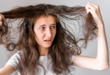Mulher com cabelo danificado e armado, mostrando frustração ao tentar controlar os fios.