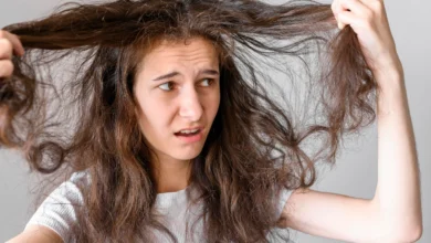 Mulher com cabelo danificado e armado, mostrando frustração ao tentar controlar os fios.