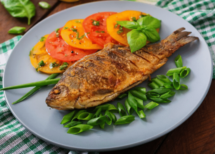 Filé de salmão grelhado acompanhado de legumes coloridos sobre prato preto