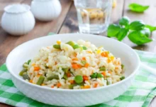 Risoto primavera com legumes frescos coloridos servido em prato branco.