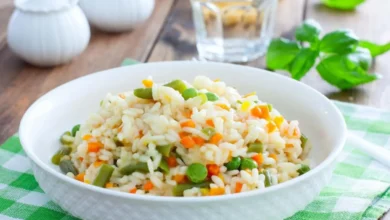 Risoto primavera com legumes frescos coloridos servido em prato branco.