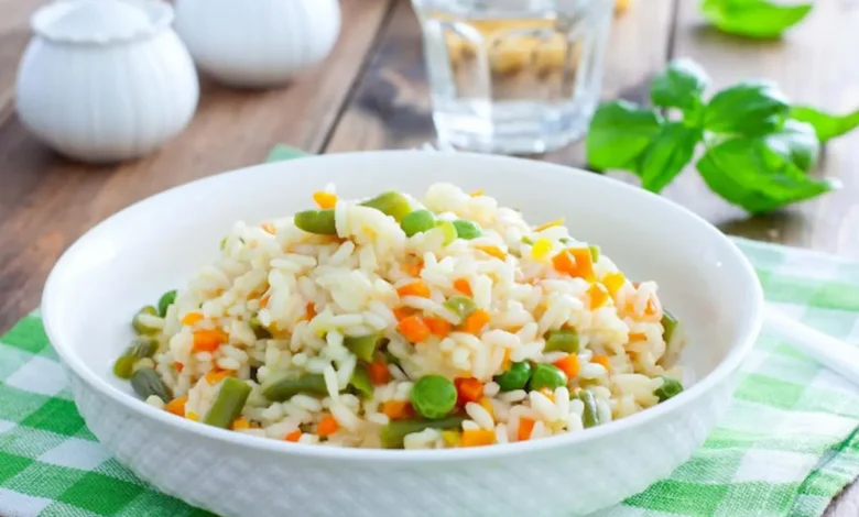 Risoto primavera com legumes frescos coloridos servido em prato branco.
