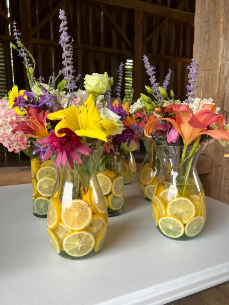 Arranjo de flores com fatias de limão em vaso transparente, criando um efeito visual criativo e decorativo.