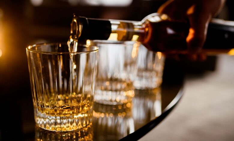 Barman servindo uma dose de bebida alcoólica em copo de cristal, ilustrando o consumo e a discussão sobre o risco de metanol.
