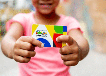 Criança segurando cartão do programa Bolsa Família.