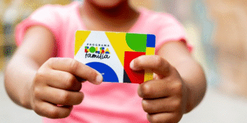 Criança segurando cartão do programa Bolsa Família.