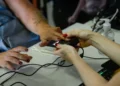 Mãos femininas utilizando oxímetro de dedo para medir batimentos e oxigenação no sangue em uma mesa com álcool em gel.