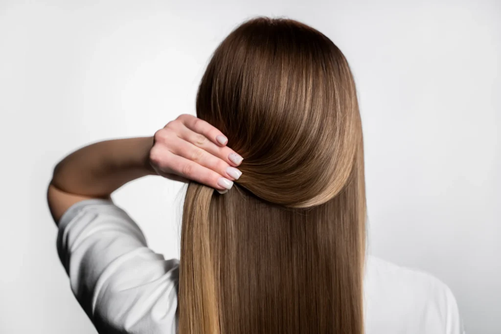 Mulher com cabelo saudável, realizando um cuidado capilar que pode ser feito em qualquer idade.