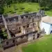 Ruínas do castelo medieval escondido no Brasil, com uma igreja ao lado, em um cenário verdejante.