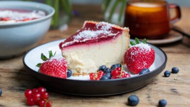 Fatia de cheesecake com calda de frutas vermelhas e morangos, representando uma receita de sobremesa com morangos.