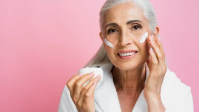 Mulher madura aplicando creme facial em sua pele, destacando os cuidados com a pele após os 50 anos.