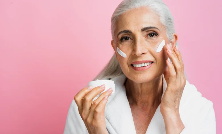 Mulher madura aplicando creme facial em sua pele, destacando os cuidados com a pele após os 50 anos.