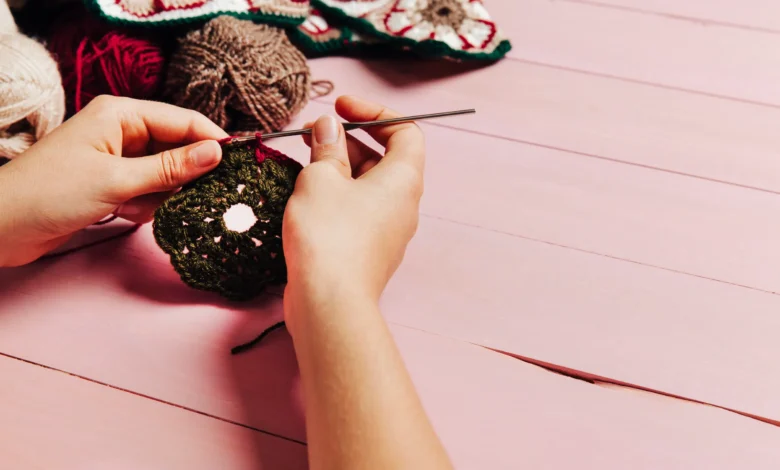 Mãos trabalhando com crochê, criando flores coloridas para decoração de primavera.