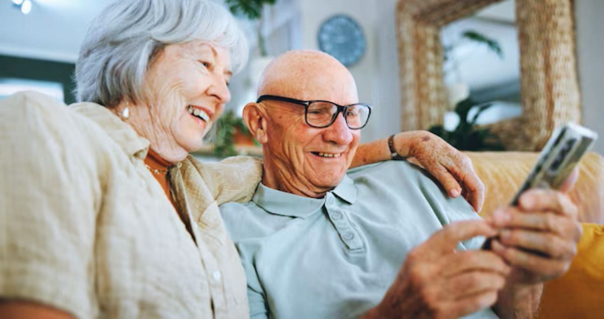Casal idoso feliz usando smartphone, explorando comunidades online.