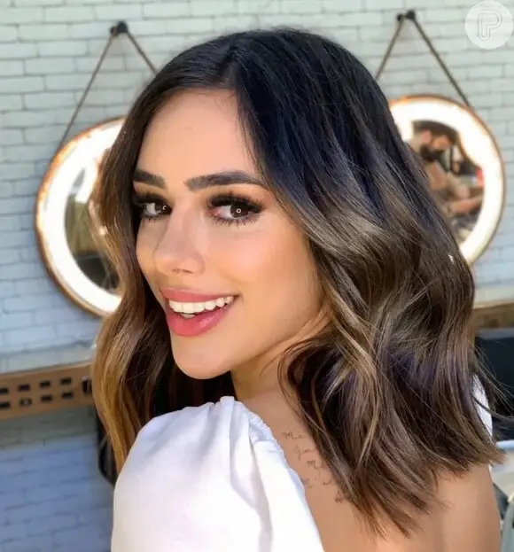 Mulher com cabelo com mechas caramelo, técnica balayage que ilumina e suaviza o rosto.