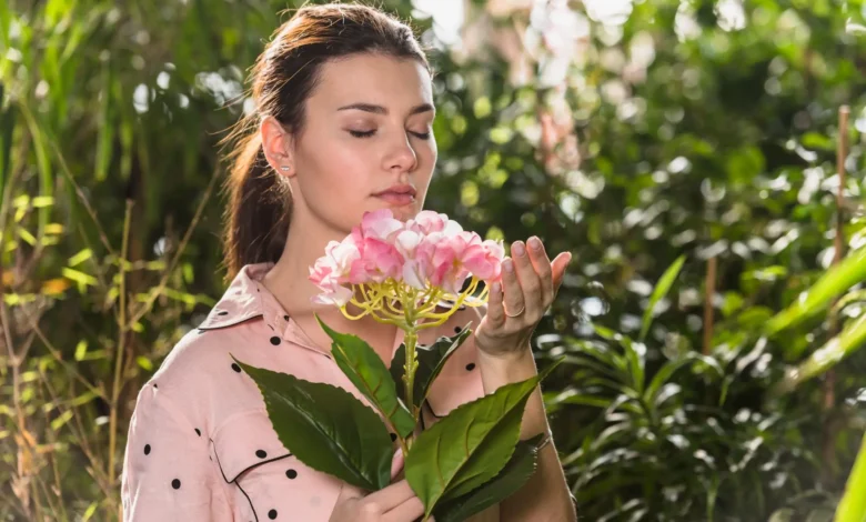 Mulher cheirando flores na primavera em um ambiente natural, simbolizando a leveza e renovação dessa estação.