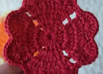 Porta-copos de crochê vermelho, com formato de flor, ideal para decorar a casa.