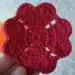 Porta-copos de crochê vermelho, com formato de flor, ideal para decorar a casa.