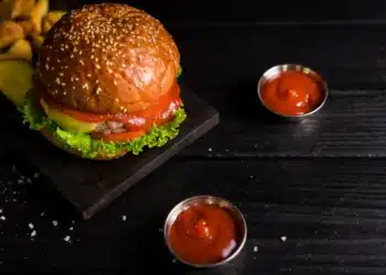 Deliciosa foto de um hambúrguer com molho, queijo, alface e ketchup, acompanhado de batatas fritas, representando o tempero secreto do Outback.