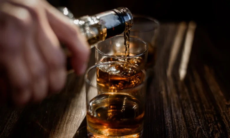 Imagem de copos de whisky sendo servidos, simbolizando os testes para detectar metanol em bebidas alcoólicas.