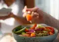 Tigela colorida com salmão fresco, legumes e folhas verdes, prato saudável e leve.