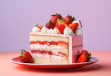 Fatia de bolo de leite ninho com morangos frescos e camadas de recheio cremoso em um prato vermelho vibrante, com fundo em degradê rosa e roxo.