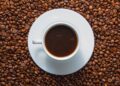 Xícara de café espresso em cima de grãos de café torrados em fundo escuro