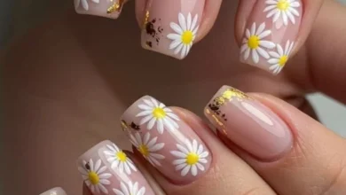 Unhas delicadas com flores brancas e amarelas, com detalhes em dourado, para a tendência de primavera de 2025.