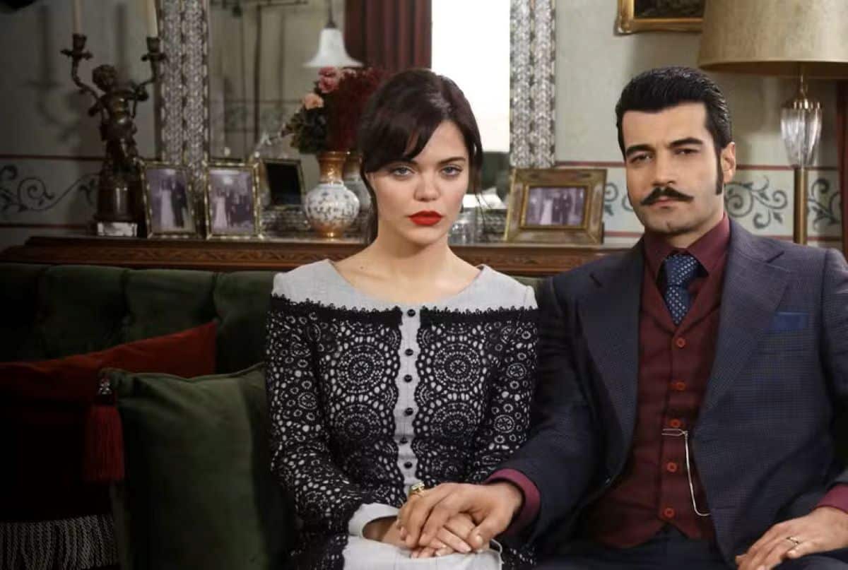 Um casal sério, com a mulher em primeiro plano olhando fixamente, ilustrando a intensidade da novela turca 'Terra Amarga' disponível no Globoplay.