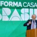 O Presidente da República, Lula, em um discurso oficial, apontando para o painel de fundo com a inscrição "REFORMA CASA BRASIL". A imagem marca o lançamento deste novo programa de habitação e melhoria residencial do governo.