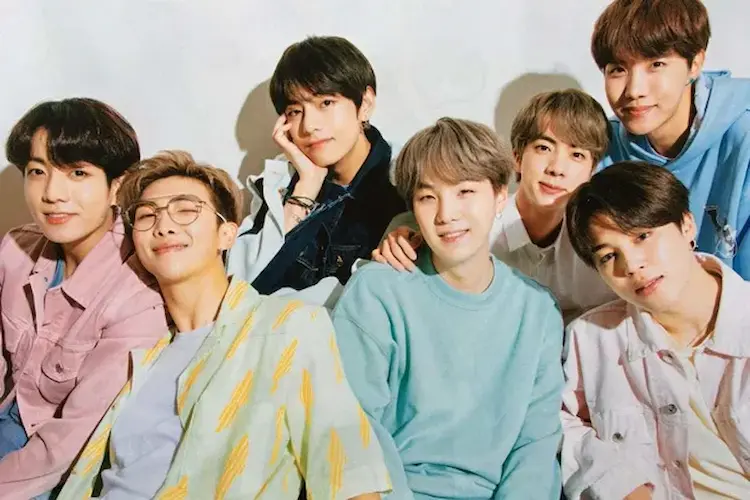 Foto do BTS com todos os membros sorrindo, posando com roupas casuais e coloridas.