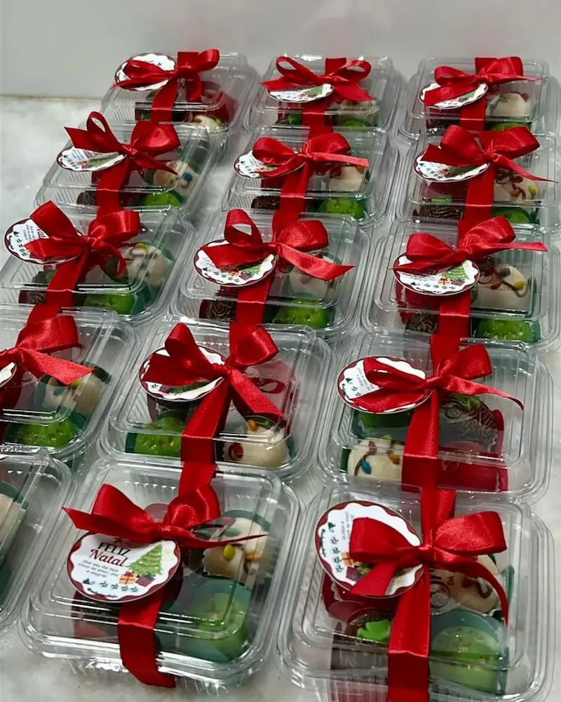 Caixinhas decoradas com doces caseiros para o Natal, embaladas com fita vermelha e adesivo temático.