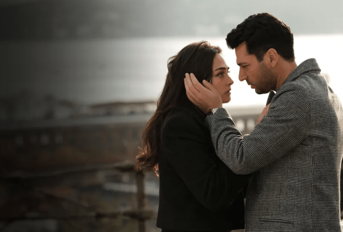 Um casal se olha intensamente, ele segurando o rosto dela com carinho e seriedade, em uma cena dramática que representa a novela turca 'Ramo: Entre o Amor e o Poder', agora no Globoplay.