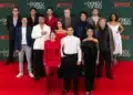 Elenco da série 'Os Donos do Jogo' posa para foto na estreia na Netflix, com trajes sofisticados, em evento de lançamento.