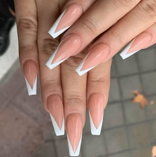 Mãos femininas com unhas longas em formato coffin, nude com ponta branca em formato de V invertido