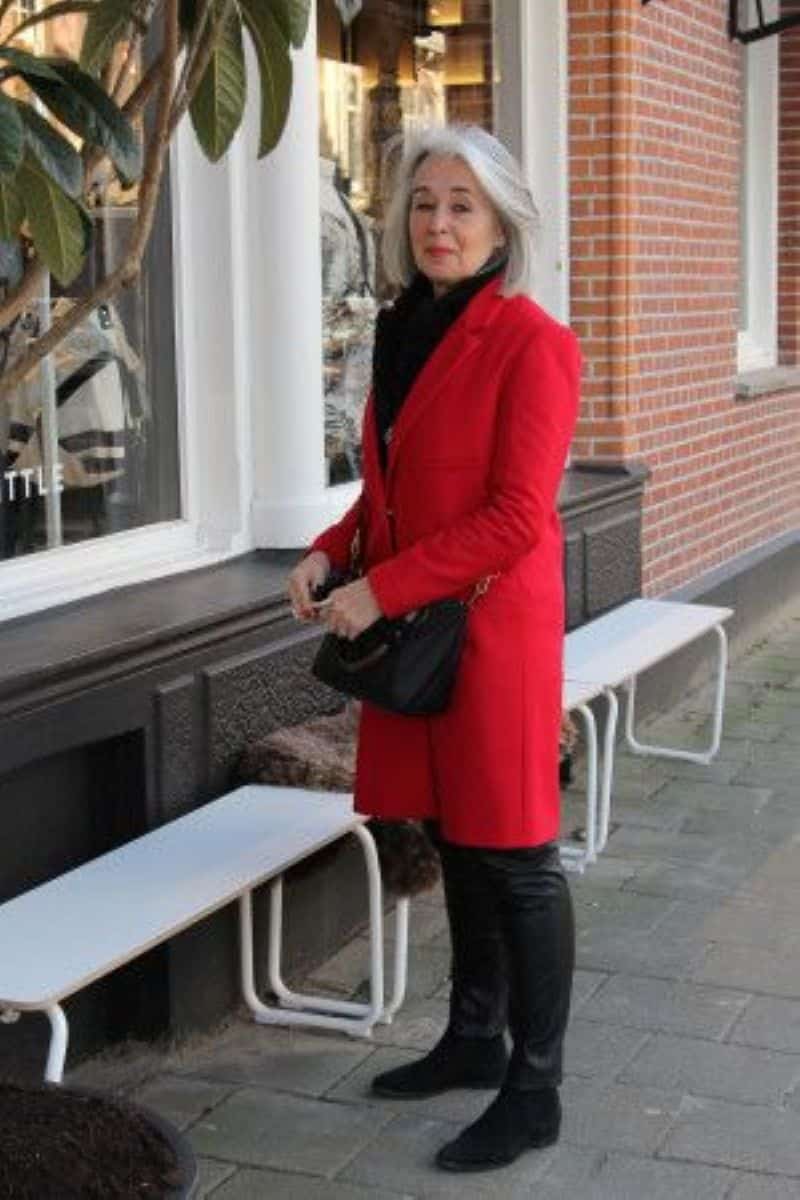 Mulher elegante com cabelo grisalho e casaco vermelho vibrante, ilustrando o contraste e o destaque que cores fortes proporcionam ao visual.