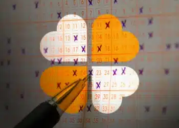 Caneta marcando números selecionados em cartão de apostas da Lotofácil sobreposto com gráfico em nuvem colorida