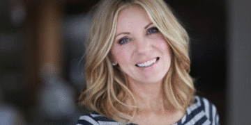 Mulher loira sorrindo com corte de cabelo na altura dos ombros que adiciona volume a rostos finos.