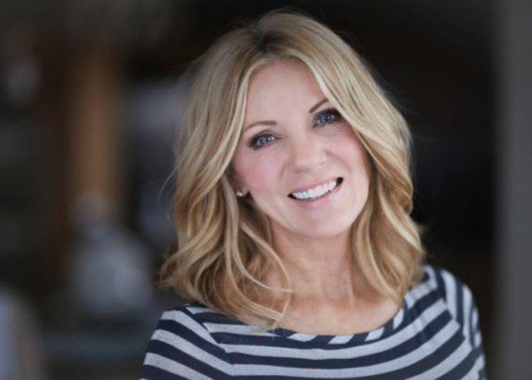 Mulher loira sorrindo com corte de cabelo na altura dos ombros que adiciona volume a rostos finos.