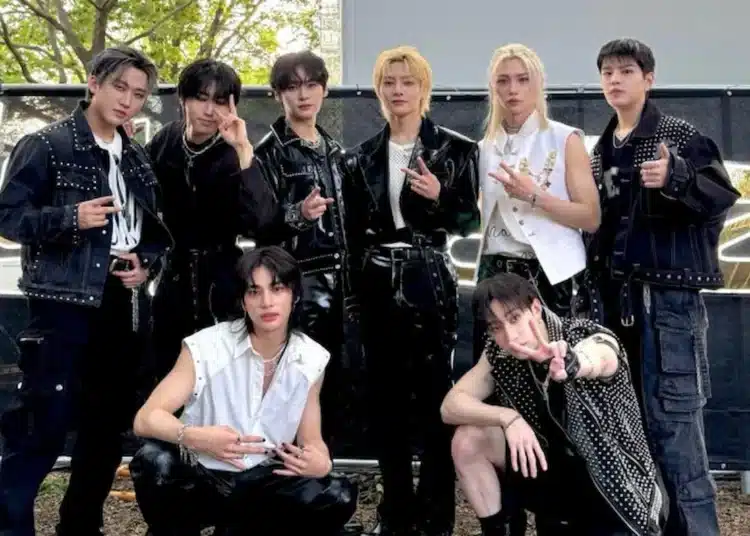 Foto do grupo Stray Kids em um evento, com todos os membros posando com gestos de mãos e looks de estilo rocker.