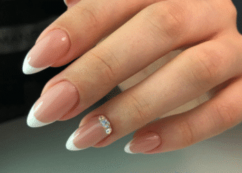 Mão com unhas compridas e bem cuidadas em estilo francesinha com detalhe de pedrarias.