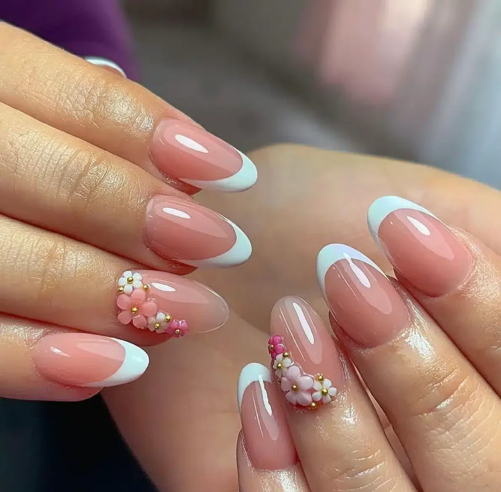 Unhas francesinhas com base nude e aplicação de flores em 3D e pérolas.