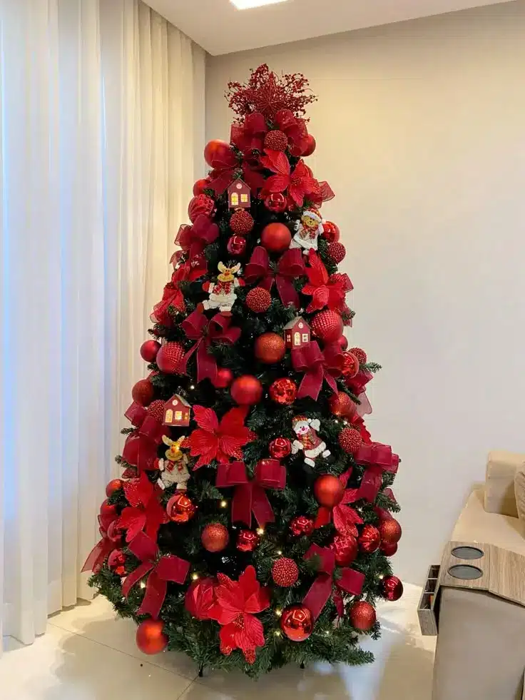 Árvore de Natal com laços de veludo vermelhos e flores artificiais. Árvore de Natal decorada com laços vermelhos, flores artificiais e detalhes natalinos, criando um visual elegante e vibrante.