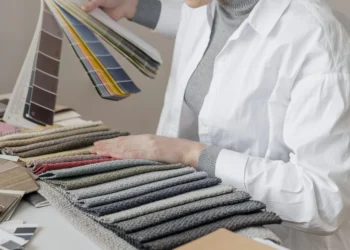 Pessoa analisando amostras de tecidos em tons de cinza enquanto escolhe cores em uma paleta, no contexto de coloração pessoal.