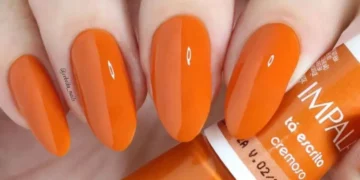 Unhas com esmalte laranja vibrante, tendência de cor para 2026.