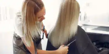 Cabeleireira corta cabelo longo e loiro em salão de beleza para um visual mais rejuvenescido.