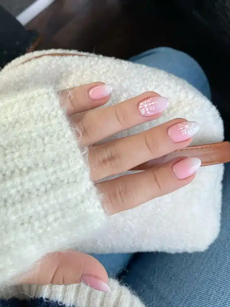 Unhas decoradas com flocos de neve delicados sobre uma base clara e translúcida.