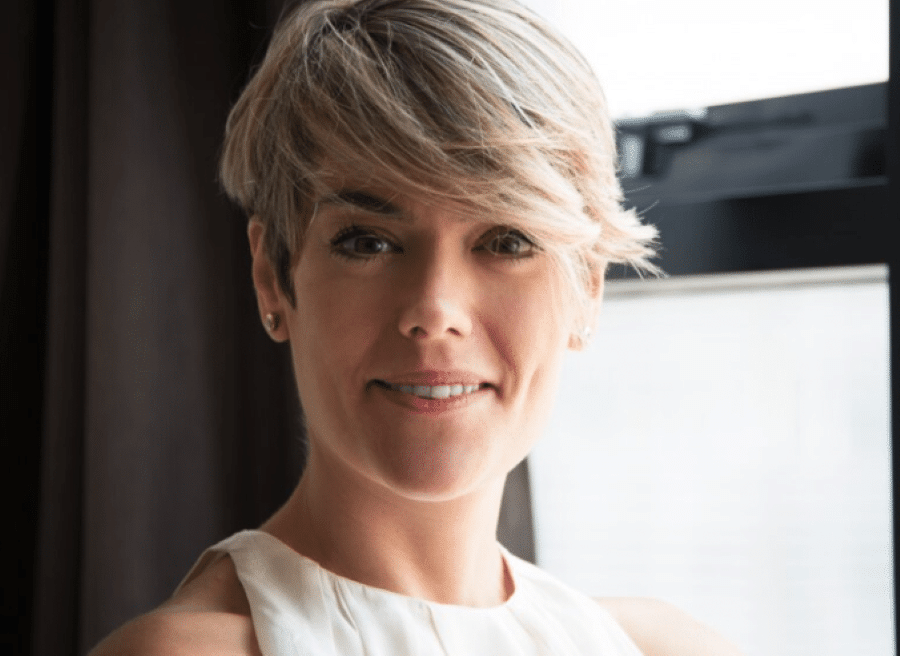 mulher sorrindo com corte de cabelo curto e volumoso, em ambiente interno iluminado