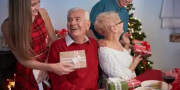 Família reunida durante as festas de Natal, trocando presentes com sorrisos e alegria, perto da árvore de Natal.